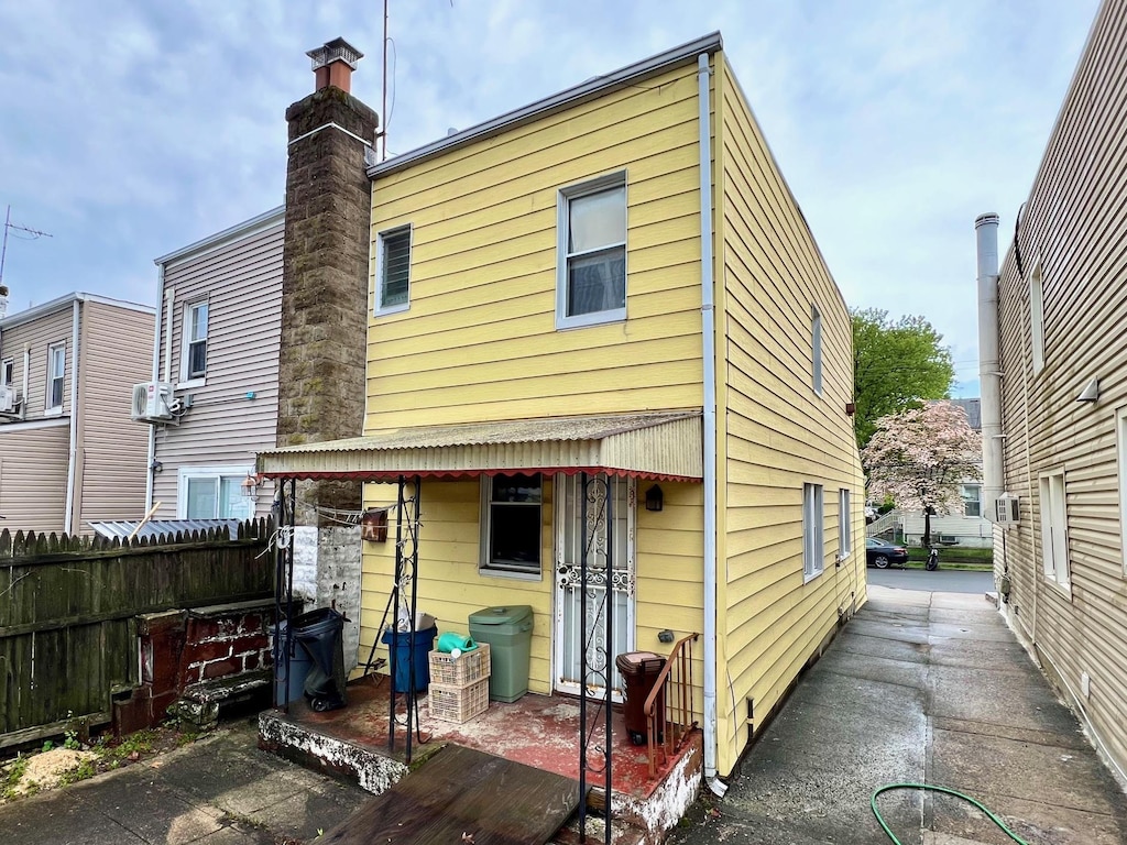 back of house with fence and a chimney