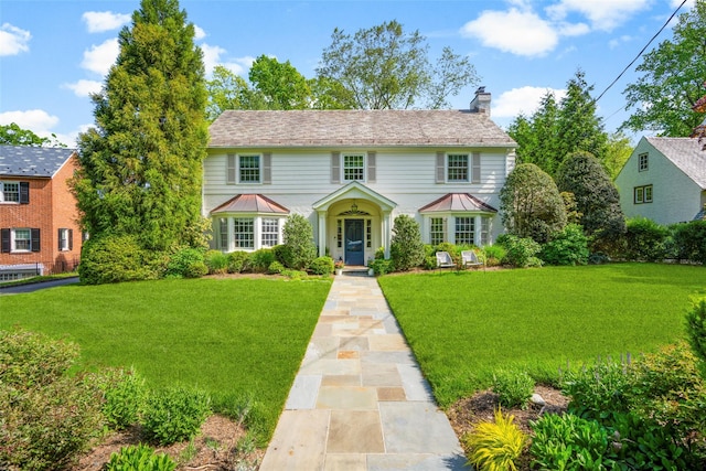 colonial house featuring a chimney and a front yard