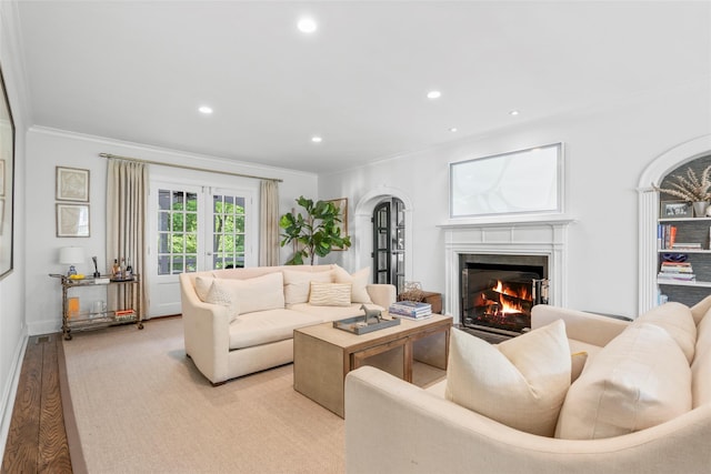 living area with ornamental molding, a premium fireplace, recessed lighting, arched walkways, and light wood finished floors