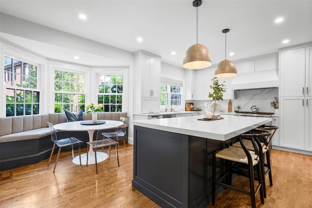 kitchen featuring custom range hood, light countertops, white cabinetry, a sink, and recessed lighting