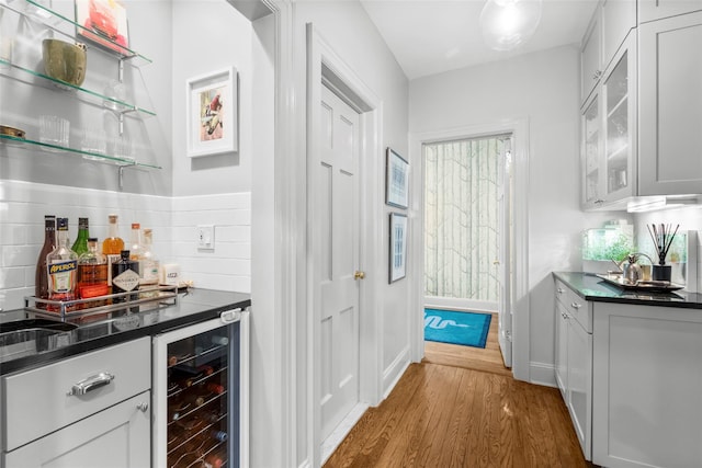 indoor dry bar with beverage cooler, dark wood-style floors, and decorative backsplash
