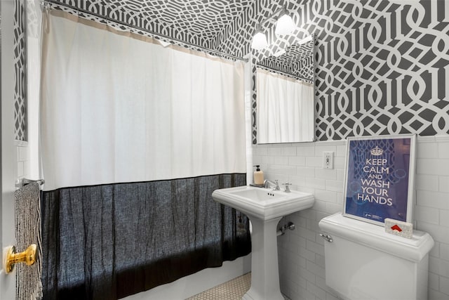 bathroom featuring toilet, wallpapered walls, tile walls, and a shower with shower curtain