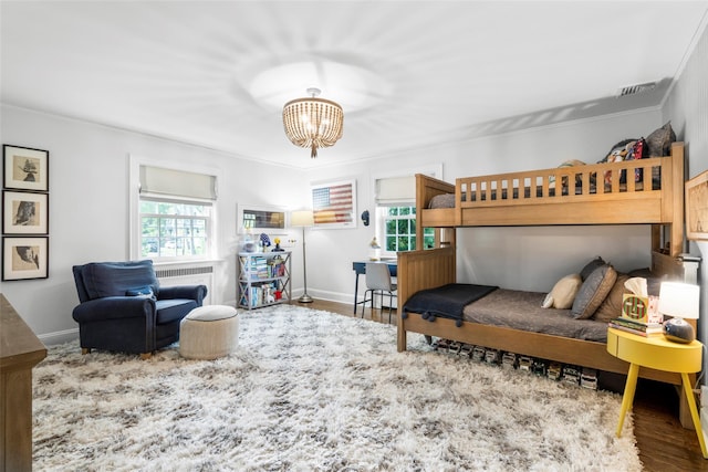 bedroom featuring a chandelier, wood finished floors, baseboards, and crown molding