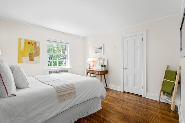 bedroom with wood finished floors, ornamental molding, baseboards, and radiator heating unit