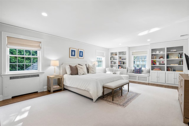 bedroom featuring radiator, wood finished floors, and recessed lighting
