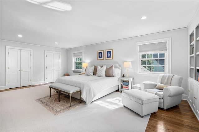 bedroom featuring recessed lighting, two closets, wood finished floors, and baseboards