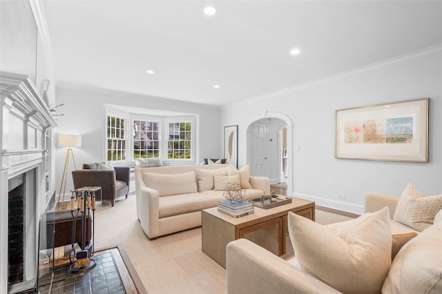 living area with arched walkways, ornamental molding, a high end fireplace, baseboards, and recessed lighting