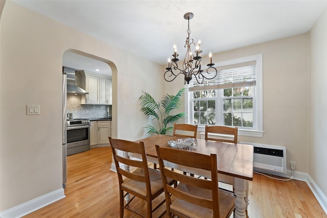 dining area with a chandelier, arched walkways, light wood-style floors, and a wall mounted air conditioner