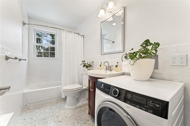 bathroom with tile walls, washer / clothes dryer, toilet, vanity, and shower / tub combo