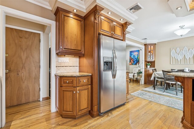 502S11th St., New Hyde Park, NY 11040 - kitchen featuring stainless steel fridge, light wood-type flooring, crown molding, brown cabinetry, and decorative backsplash