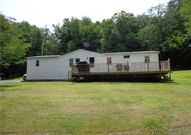rear view of property featuring a deck, a yard, and view of wooded area