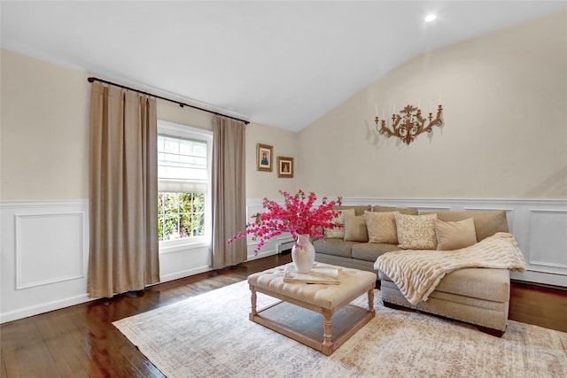 living area with lofted ceiling, hardwood / wood-style floors, wainscoting, a decorative wall, and a baseboard heating unit
