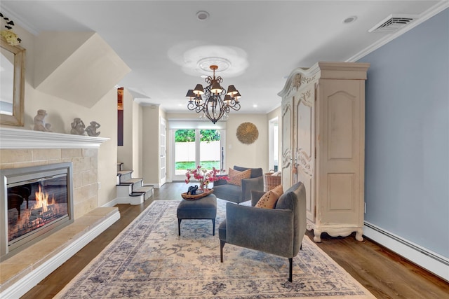 living area featuring a baseboard radiator, ornamental molding, dark wood-style floors, a chandelier, and a tiled fireplace