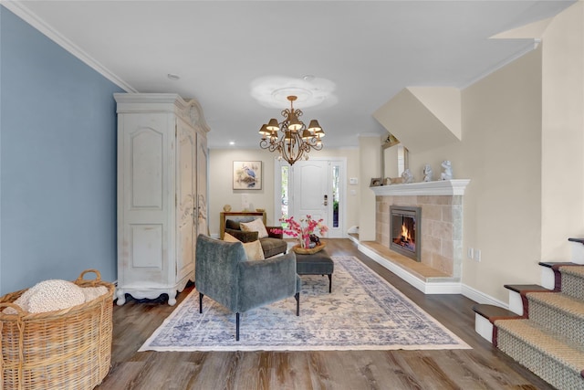 living room with ornamental molding, wood finished floors, a chandelier, a fireplace, and baseboards