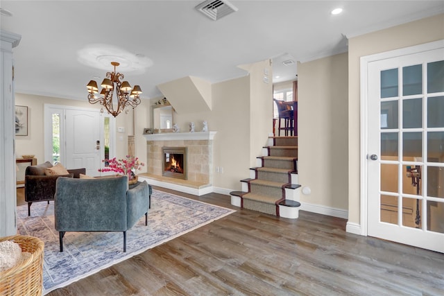 living area featuring wood finished floors, healthy amount of natural light, stairs, baseboards, and crown molding