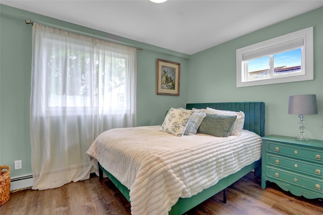 bedroom with wood finished floors and a baseboard radiator