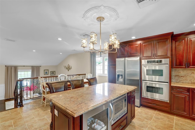 kitchen with appliances with stainless steel finishes, healthy amount of natural light, a chandelier, reddish brown cabinets, and recessed lighting
