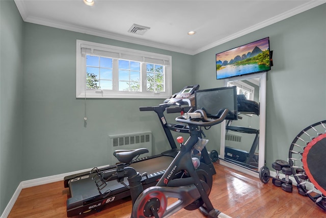 workout area with wood finished floors, recessed lighting, radiator heating unit, crown molding, and baseboards