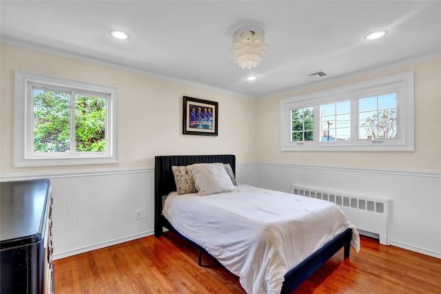 bedroom featuring radiator, a wainscoted wall, wood finished floors, and recessed lighting