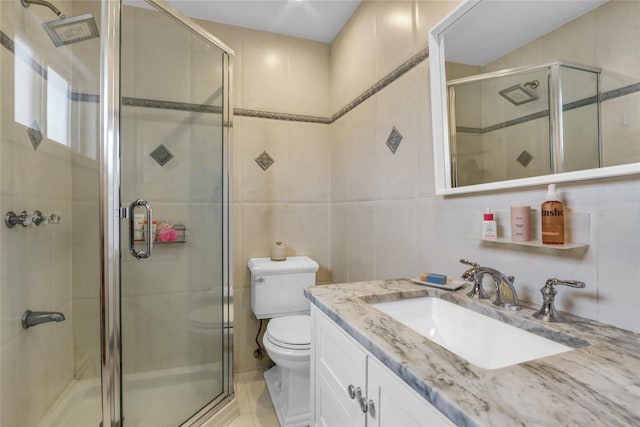 full bath with tile walls, a stall shower, vanity, and toilet