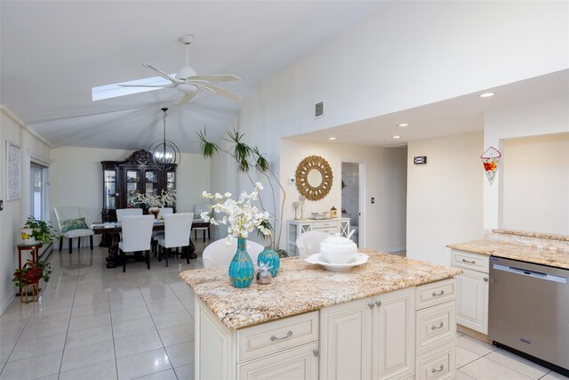 kitchen with dishwasher, a ceiling fan, a skylight, light tile patterned flooring, and light stone countertops