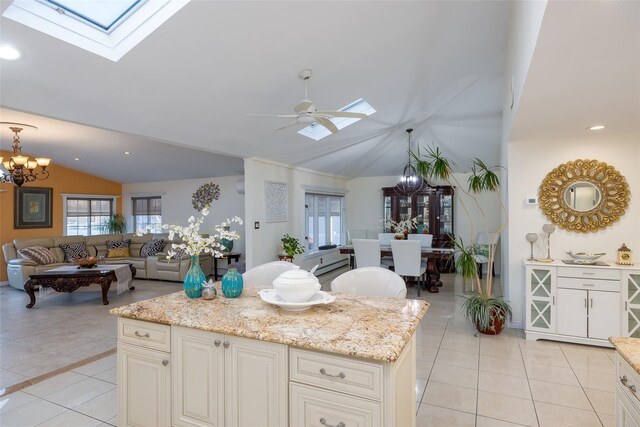 kitchen with a chandelier, vaulted ceiling, a skylight, open floor plan, and light tile patterned flooring