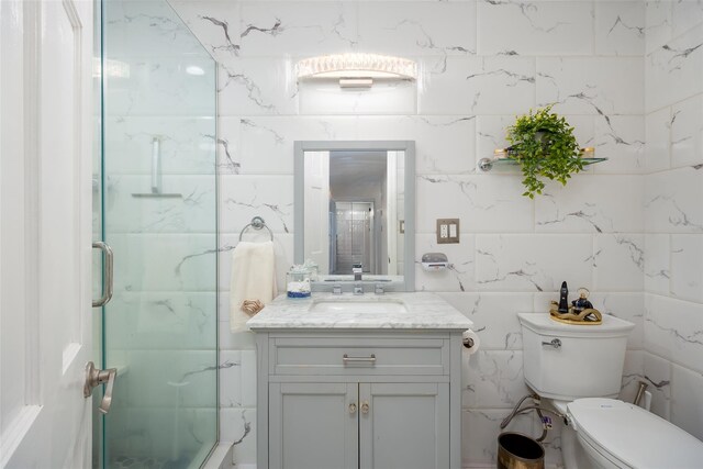 full bathroom featuring tile walls, a stall shower, vanity, and toilet