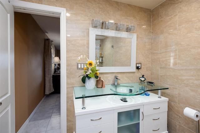 bathroom with tile walls, tile patterned flooring, vanity, and baseboards