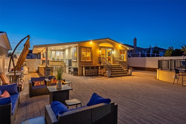 rear view of property featuring an outdoor living space, stucco siding, and a fenced backyard