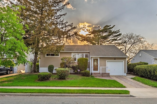 view of front of home featuring an attached garage, driveway, and a yard