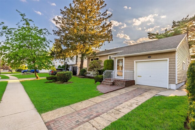 view of front of home featuring a front lawn, driveway, an attached garage, and roof with shingles