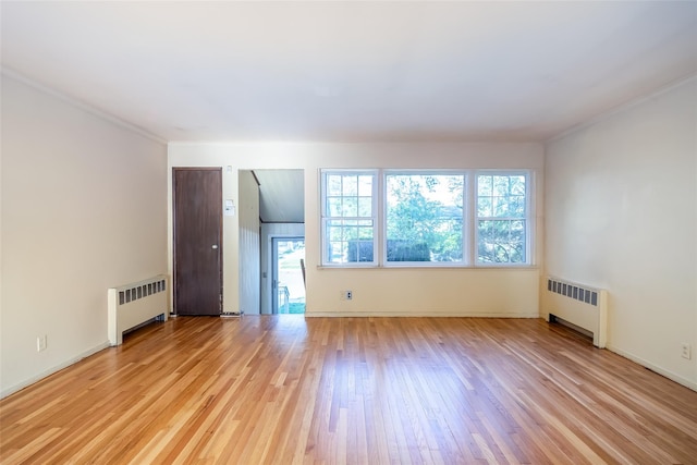 unfurnished living room featuring radiator heating unit, light wood-style flooring, baseboards, and crown molding
