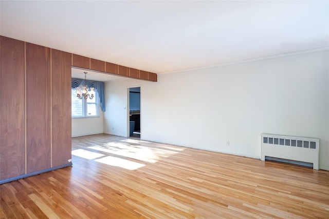 unfurnished living room with radiator, a chandelier, and light wood-style floors