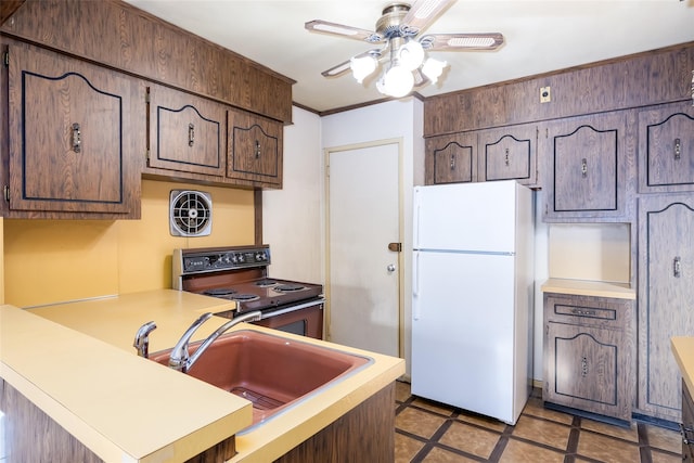 kitchen featuring freestanding refrigerator, electric range oven, a sink, and light countertops