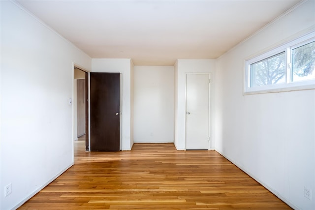 unfurnished bedroom with light wood finished floors and crown molding