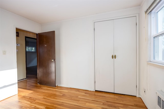 unfurnished bedroom featuring light wood-type flooring, a closet, and ornamental molding