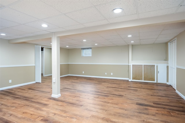 finished basement with wood finished floors, baseboards, a drop ceiling, and recessed lighting