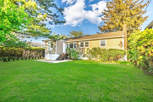 back of house featuring a yard, a chimney, and a patio area