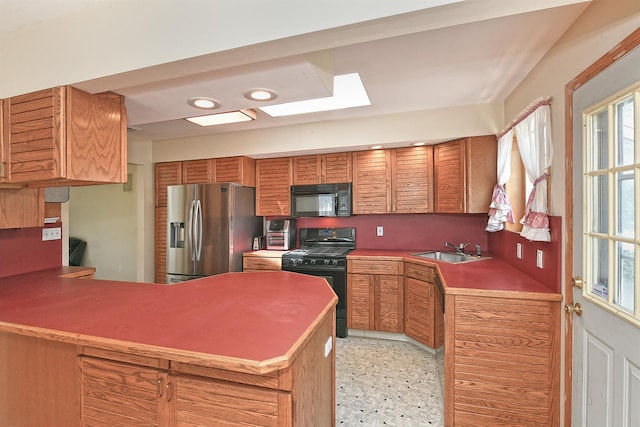 64 S Nassau St, Bethpage, NY 11714 - kitchen with black appliances, a sink, a skylight, a peninsula, and brown cabinetry
