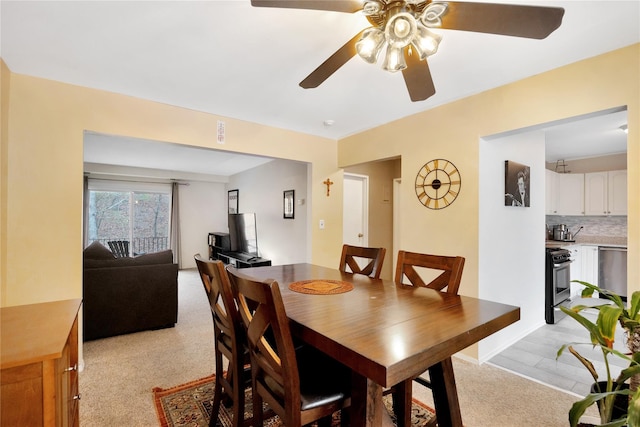 dining area with a ceiling fan and light carpet
