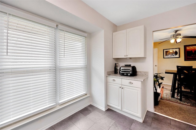 kitchen with white cabinetry, a ceiling fan, baseboards, and light tile patterned floors