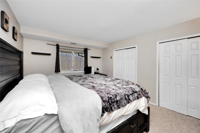 bedroom featuring light carpet and multiple closets