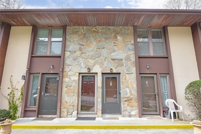 property entrance featuring stone siding and stucco siding