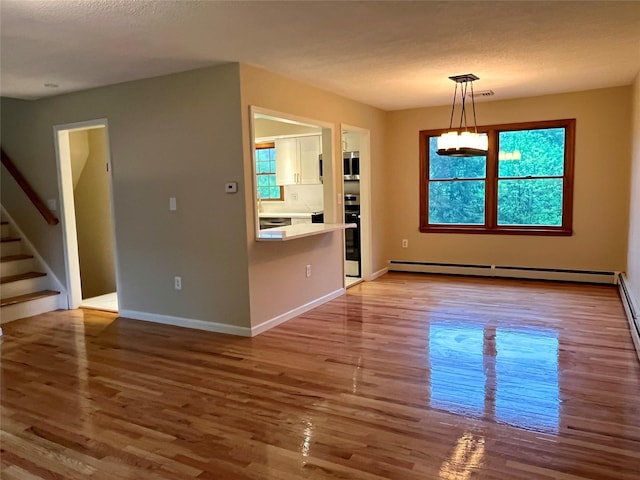 51 Pine Ct, Middletown, NY 10941 - unfurnished dining area with baseboard heating, wood finished floors, stairs, and plenty of natural light