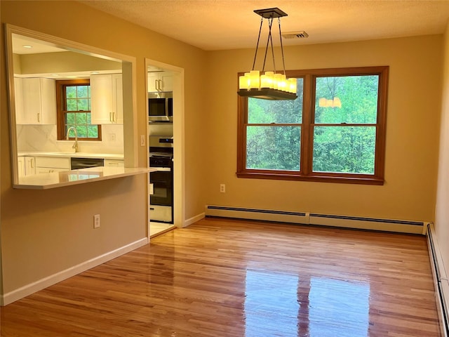 51 Pine Ct, Middletown, NY 10941 - unfurnished dining area with a baseboard heating unit, light wood-type flooring, a chandelier, and baseboards