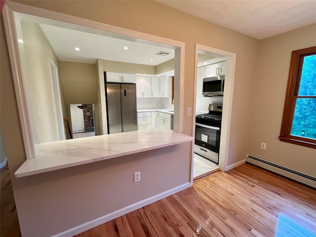 51 Pine Ct, Middletown, NY 10941 - kitchen featuring stainless steel appliances, white cabinets, light stone countertops, light wood finished floors, and a peninsula