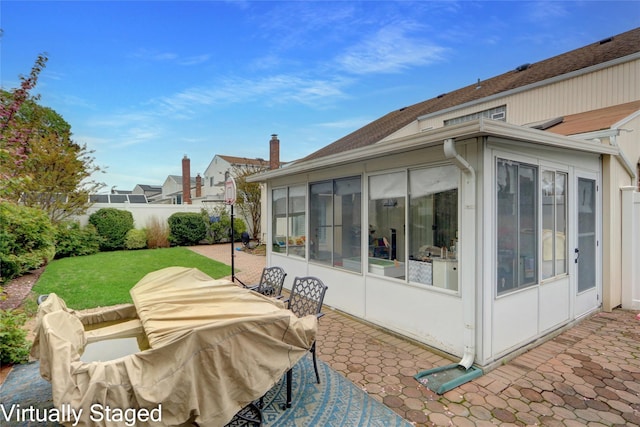 back of property featuring a sunroom, a patio, and fence