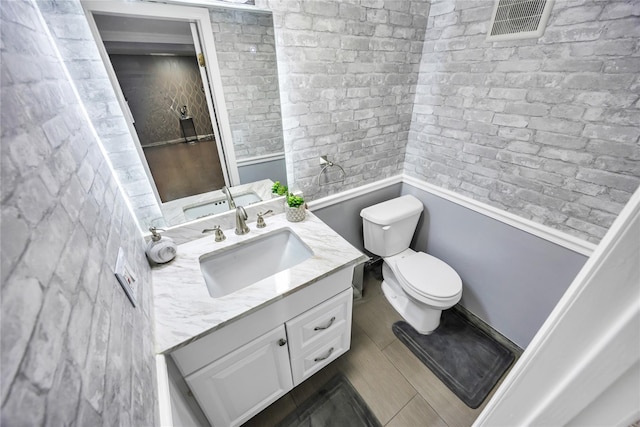 bathroom with a wainscoted wall, toilet, and vanity