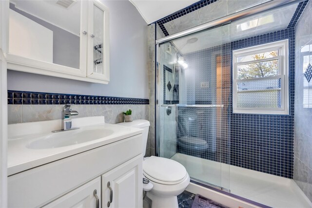 full bathroom with tile walls, toilet, a stall shower, and vanity