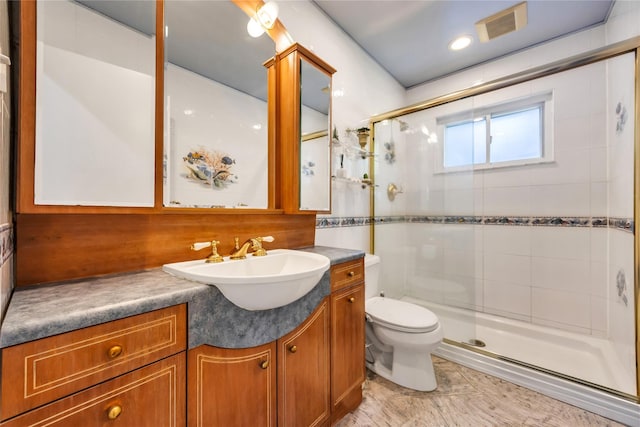 bathroom featuring a shower stall, toilet, and vanity